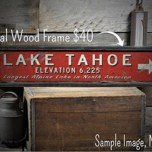 Puede incluir: Un letrero rojo y blanco con letras negras que dice "LAKE TAHOE ELEVATION 6,225 Largest Alpine Lake in North America". El letrero tiene un marco negro y una flecha blanca que apunta hacia la derecha. El letrero est&aacute; sobre un fondo de madera. Agrega un marco de madera opcional por 40 &euro;.