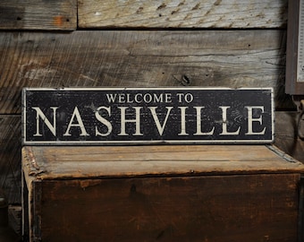 May include: Black and white wooden sign with the text "Welcome to Nashville" against a rustic wooden backdrop.