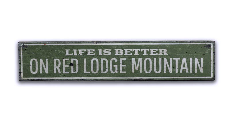 May include: A green wooden sign with white text that reads "Life is better on Red Lodge Mountain".