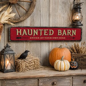 May include: A rectangular red sign with black edges featuring the text HAUNTED BARN in large beige letters and the text ENTER AT YOUR OWN RISK in smaller beige letters, accompanied by a black arrow graphic pointing to the right side.