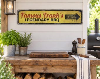 May include: A rectangular metal sign with a distressed yellow background and black border. The text reads Famous Frank's LEGENDARY BBQ in red and black lettering, with a black arrow pointing right containing the text ENTRANCE & PARKING.