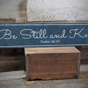 May include: A blue wooden sign with white text that reads "Be Still and Know" with the scripture reference "Psalm 46:10" underneath.