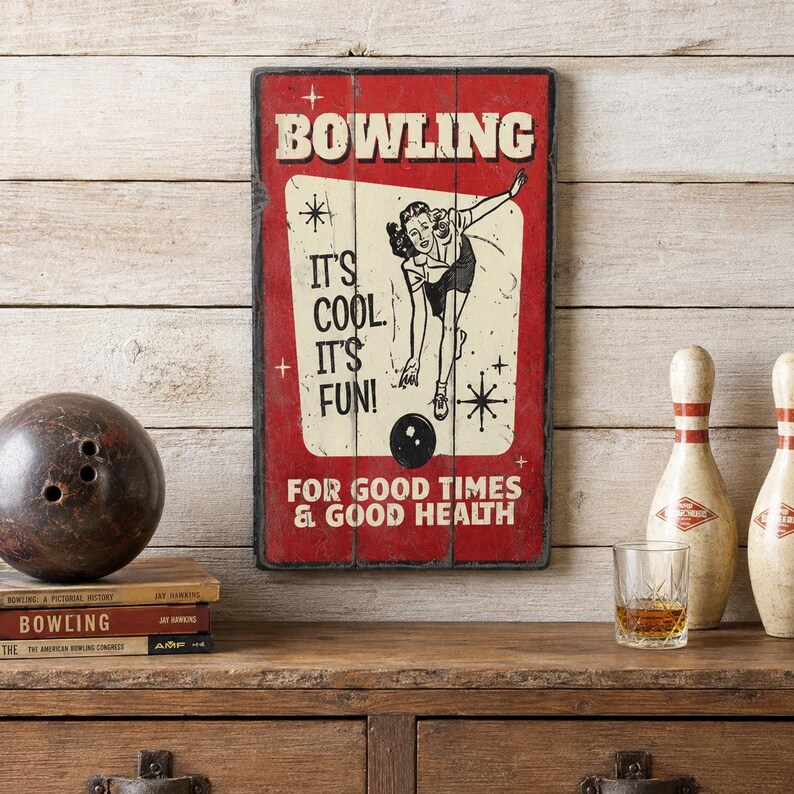 May include: A rectangular wooden wall sign with a red background and a cream-coloured centre panel. It features a black and white illustration of a person bowling, with the text BOWLING, IT'S COOL. IT'S FUN! FOR GOOD TIMES & GOOD HEALTH.