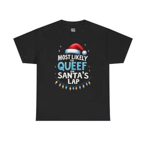 May include: Black t-shirt with a Christmas-themed graphic. The design features a Santa hat, twinkling stars, and the text "MOST LIKELY TO QUEEF ON SANTA'S LAP" in white and blue, with a string of colorful lights at the bottom.