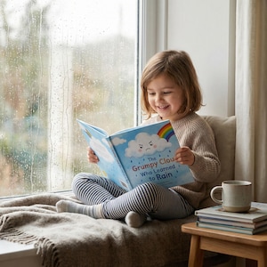 Op de afbeelding: Een kind leest een boek met de titel "The Grumpy Cloud Who Learned to Rain" bij een raam. De kaft van het boek toont een chagrijnige wolk, een regenboog en regendruppels. Het kind draagt een beige trui en een gestreepte broek.
