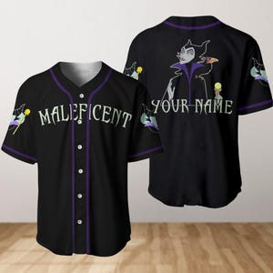 Puede incluir: Jersey de béisbol negro con ribetes morados con Maléfica de La Bella Durmiente de Disney. La parte delantera del jersey dice "MALeficent" y la parte trasera dice "YOUR NAME".