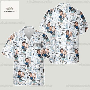 Puede incluir: Una camisa blanca de botones con un patrón de temática de golf. El patrón presenta a un golfista de dibujos animados sosteniendo un palo de golf, pelotas de golf, bolsas de golf y carritos de golf. La camisa tiene una etiqueta de nombre que dice "MICHAEL".
