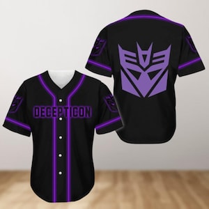 Pode incluir: Camisola de beisebol preta com guarnição roxa e a palavra "DECEPTICON" na frente. A parte de trás da camisola apresenta um logotipo roxo Decepticon.