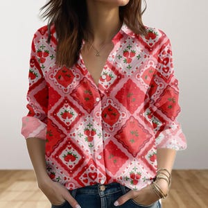 May include: A red and white button-down shirt with a strawberry pattern. The long-sleeved shirt features a repeating design of strawberries, hearts, and decorative squares. The shirt has a collared neckline and is made of a lightweight fabric.