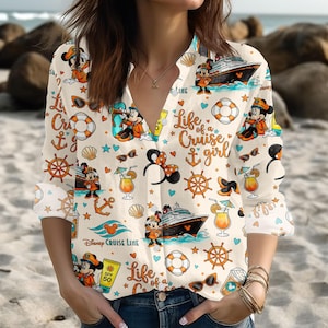Könnte beinhalten: Cremefarbenes Hemd mit Knopfleiste und einem Kreuzfahrt-Motiv mit Mickey und Minnie Mouse, Kreuzfahrtschiffen, Ankern und dem Text "Life of a Cruise Girl". Das Hemd hat lange Ärmel und einen V-Ausschnitt.