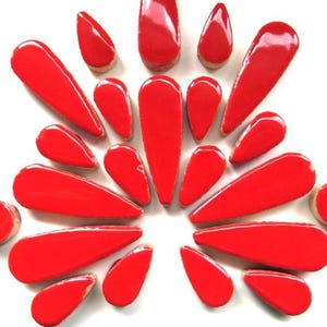 May include: A collection of glossy, teardrop-shaped red objects arranged in a radial pattern against a white background. The objects vary in size, with a high-shine finish, creating a visually striking display.