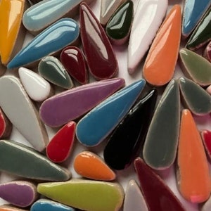 May include: A collection of colourful ceramic teardrop-shaped tiles in various shades of blue, green, red, orange, purple, and grey.