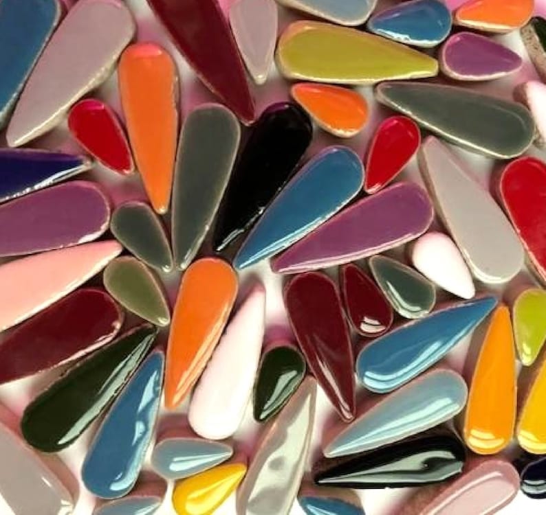 May include: A collection of colourful ceramic teardrop-shaped tiles in various shades of red, orange, yellow, green, blue, purple, brown, black, and white.