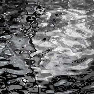 May include: Abstract black and white photograph of rippling water. The water is still and reflects the light, creating a pattern of swirls and circles.