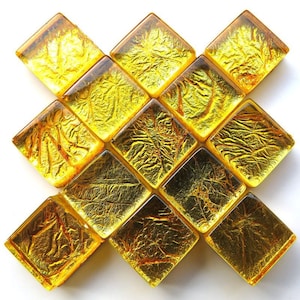 May include: A set of 12 gold-toned square tiles with a textured surface. The tiles are arranged in a diamond pattern.