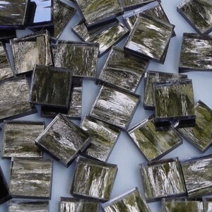 May include: A pile of small, square, green and silver mosaic tiles. The tiles have a metallic sheen and a textured surface.