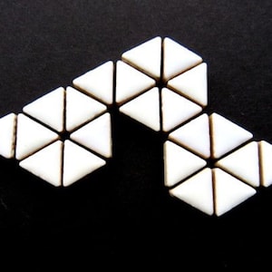 May include: Arrangement of white triangular tiles on a black background. The tiles are arranged in a geometric pattern, with each tile touching its neighbors. The overall effect is a modern, abstract design.