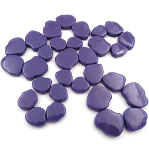 May include: A collection of 25 purple glass mosaic tiles in a variety of irregular shapes. The tiles are smooth and glossy.