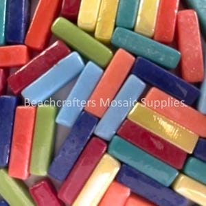 Puede incluir: Surtido de azulejos de mosaico de vidrio de colores en varios tonos de azul, verde, amarillo, rojo y naranja. Los azulejos son de forma rectangular y tienen un acabado brillante.