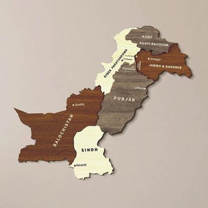 May include: A wall-mounted wooden map of Pakistan featuring distinct provinces in varying shades of brown, tan, and cream wood grain. The map includes labeled regions such as Balochistan, Sindh, Punjab, and Jammu & Kashmir with city markers.