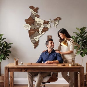 May include: A wall-mounted wooden map of India featuring a multi-tonal design with varying shades of brown and cream, displaying state boundaries and labels, positioned above a wooden desk with a desk lamp and office supplies.