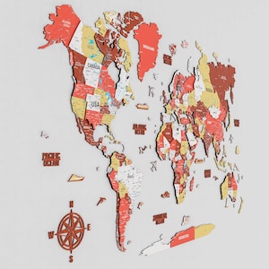 May include: A wooden world map with a three-dimensional effect, featuring countries in shades of red, yellow, and brown. The map includes labels for oceans and continents, and a compass rose. The USA and Canada are clearly visible.