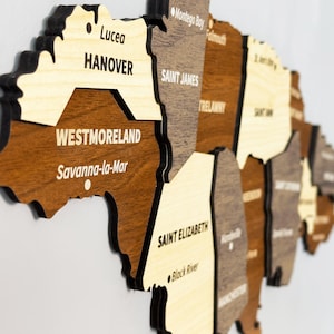 May include: A wooden map of Jamaica with the names of the parishes and major towns printed on each piece. The map is made of different shades of brown wood and is assembled in a 3D style.