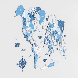 May include: A three-dimensional world map in shades of blue, mounted on a white wall. The map includes country names and ocean labels. A compass rose is positioned near the Pacific Ocean. The map is a decorative piece.