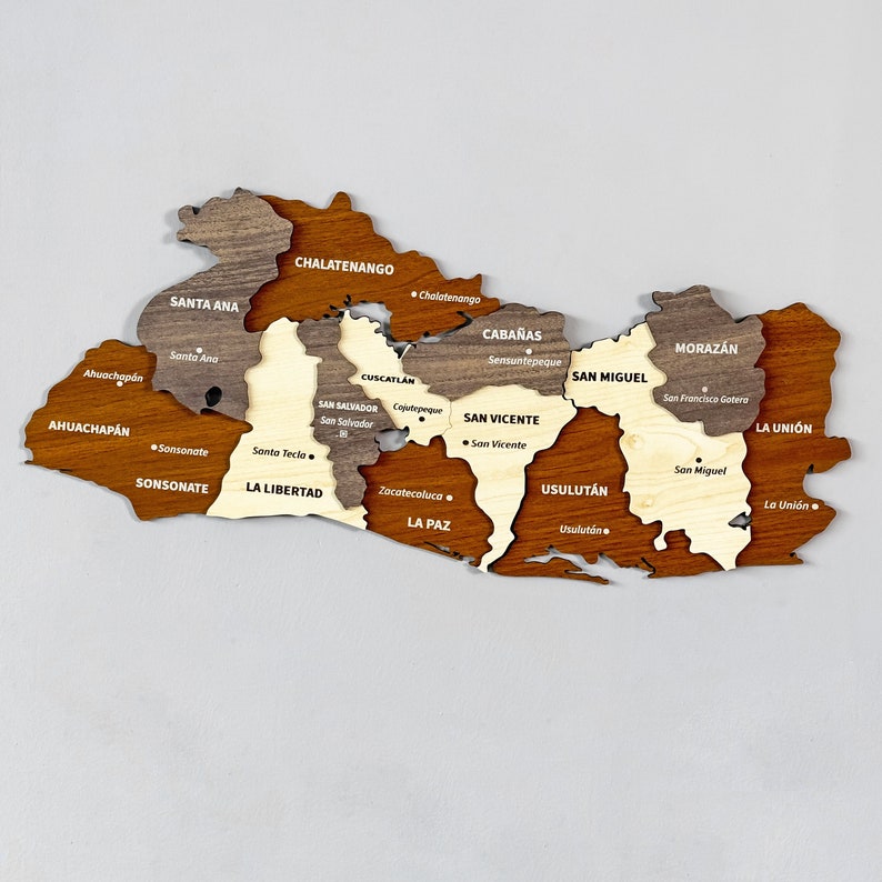 May include: A wooden map of El Salvador, divided into 14 departments, each with its name and capital city labeled. The map is made of different shades of brown wood, with each department highlighted in a different shade.