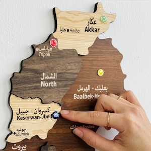 Op de afbeelding: Een houten wandkaart van Libanon met verschillende lichte en donkere houtsegmenten voor de regio's. De kaart bevat gegraveerde tekst in het Arabisch en Engels voor locaties zoals Akkar, Tripoli, North, Baalbek-Hermel en Keserwan-Jbeil.