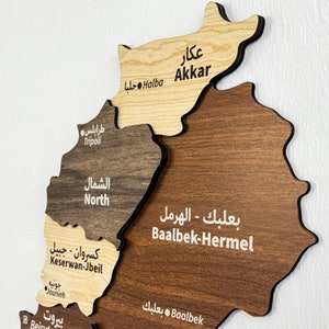 May include: A wooden map of Lebanon divided into its 10 governorates. The map is labeled in both Arabic and English. The governorates are Akkar, North, Baalbek-Hermel, Keserwan-Jbeil, Beirut, Mount Lebanon, South, Bekaa, Nabatieh, and Tripoli.