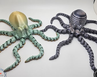 May include: Two 3D printed octopus figurines. One is green and gold, the other is black and silver. Both have segmented tentacles.