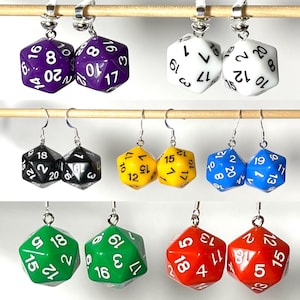 May include: A set of 10 pairs of dangle earrings featuring colorful dice charms. Each pair of earrings has a different color dice charm, including purple, white, yellow, blue, green, and red.
