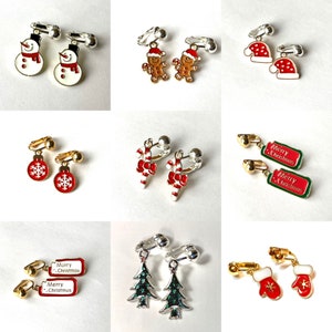 May include: A collection of Christmas-themed earrings. Designs include snowmen, gingerbread men, Santa hats, ornaments, candy canes, gift tags with "Merry Christmas", Christmas trees, and mittens. Each pair has a silver or gold-tone clip-on backing.