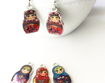 May include: A set of five silver charm pendants featuring colorful Russian nesting doll designs. The dolls are painted with traditional patterns and have a whimsical, folk art style.