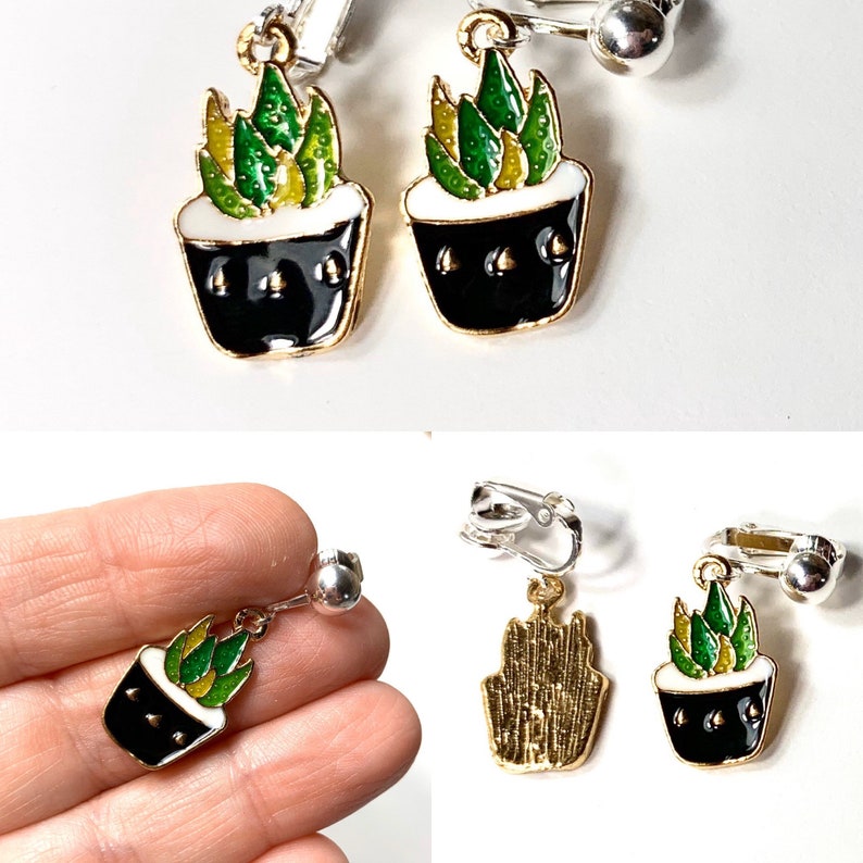 May include: A pair of gold-tone clip-on earrings featuring a black potted succulent plant with green and yellow leaves.