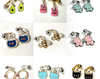 May include: A set of 10 pairs of clip-on earrings featuring various designs, including avocado, guitar, elephant, goldfish, bee, cat, and a circle with colorful beads. The earrings are made of metal and have a gold or silver finish.