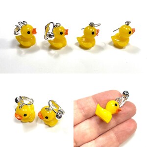 May include: A pair of yellow rubber ducky clip-on earrings. The earrings are made of a yellow rubber ducky with orange beak and black eyes. The ducky is attached to a silver clip-on earring.