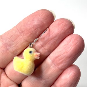 May include: A pair of yellow fuzzy duck earrings with silver hooks. The duck is a popular children's bath toy.