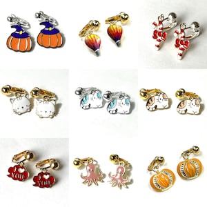 May include: Assortment of colorful clip-on earrings featuring various designs, including pumpkins, hot air balloons, candy canes, cats, octopuses, and clouds with the text "I love you".