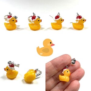 May include: Yellow rubber ducky earrings with a red Santa hat. The earrings are silver and have a hook closure.