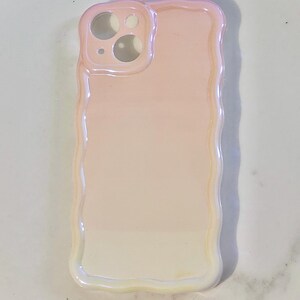 May include: A pearlescent phone case with a wavy edge. The case has a gradient of colors, transitioning from a light pink to a soft white. The camera cutouts are visible at the top, and the case is designed to fit a smartphone.