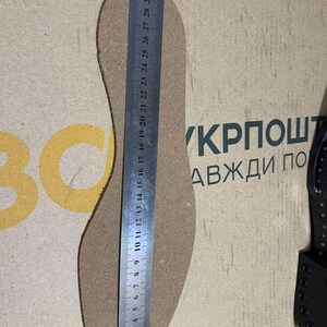 Puede incluir: Una plantilla de zapato de color beige se mide con una regla met&aacute;lica. La plantilla se coloca sobre una superficie marr&oacute;n claro. La regla muestra medidas en cent&iacute;metros. El texto "BC" y "КРПОШТ АВЖДИ ПО" son visibles.