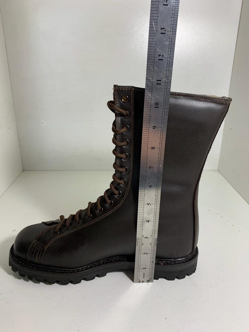 May include: A brown leather boot with a lace-up design. The boot is approximately 13 inches tall. The sole is black and rugged. The boot is made of a dark brown leather material.