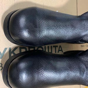 Puede incluir: Un par de botas de cuero negro con punteras redondeadas y empeines texturizados. Las botas tienen una suela oscura y un brillo sutil. Dise&ntilde;o sencillo y cl&aacute;sico.