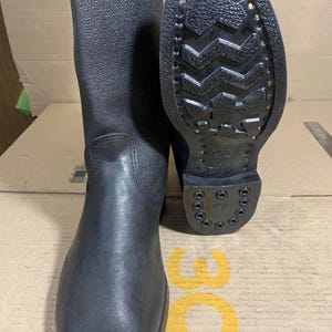 Op de afbeelding: Een paar zwarte leren laarzen met een rits aan de zijkant. De laarzen hebben een dikke zool met een profielpatroon. De zool is gemarkeerd met de tekst "25.5 5010".