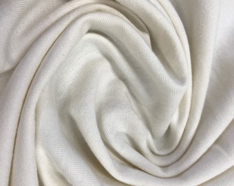 May include: Close-up of a soft, white fabric with a ribbed texture. The fabric is folded and draped, creating a smooth, flowing look.