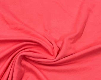 May include: A close-up of a smooth, coral pink fabric with a soft, wrinkled texture.