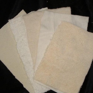 May include: A collection of six different fabric swatches in various shades of beige and cream. The swatches are made of different textures, including smooth, textured, and terry cloth.