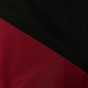 May include: A fabric swatch with a diagonal line dividing the fabric into two sections. One section is black and the other section is burgundy.